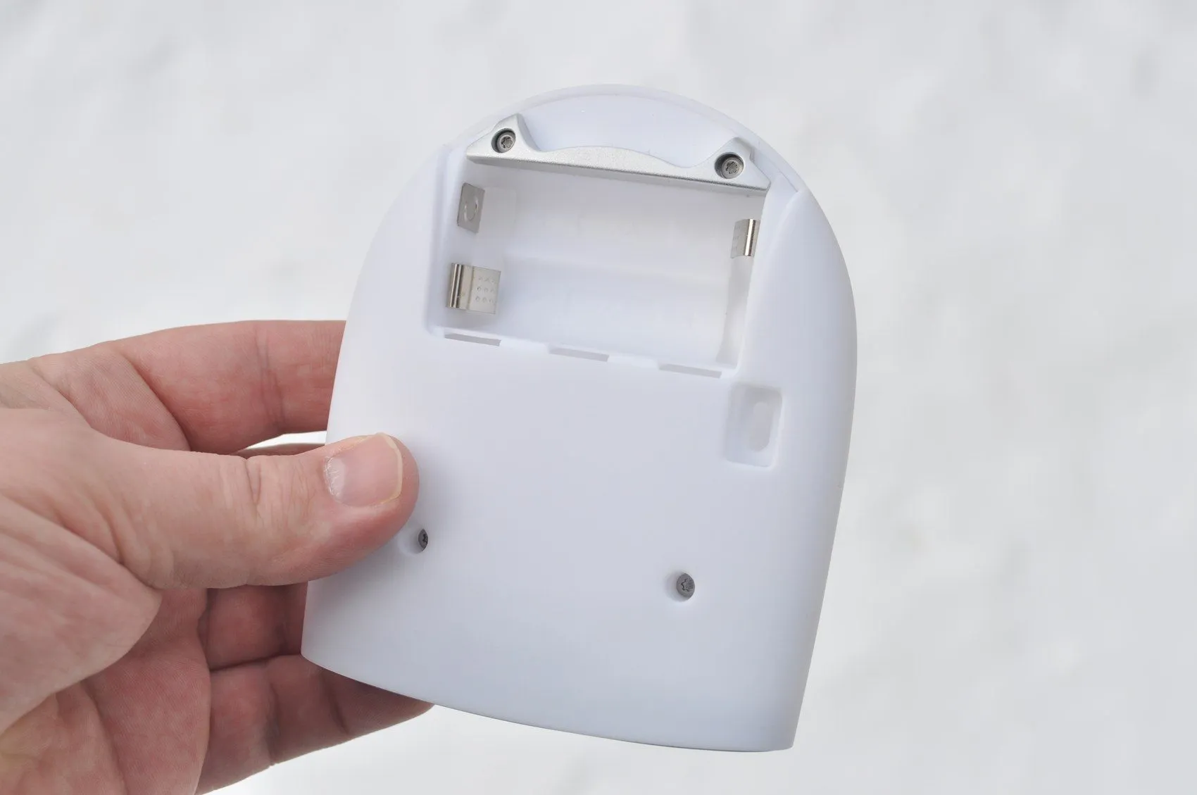Rear of the white recorder enclosure held in a hand, with the battery bay open
