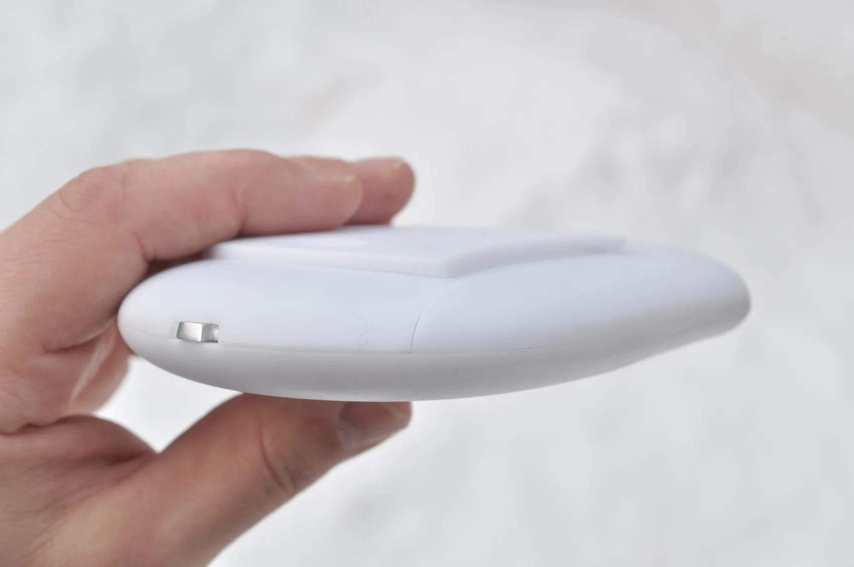 Thin white prototype enclosure held edge-on in a hand