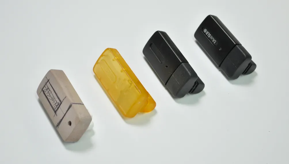 Four BlueSLR GPS dongle prototypes from sketched foam block to translucent resin to final black housing
