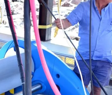Technician handling hoses and cables on a blue water-power turbine prototype