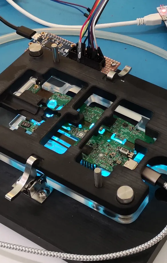 Circuit boards in a custom test fixture wired to a microcontroller on a workbench