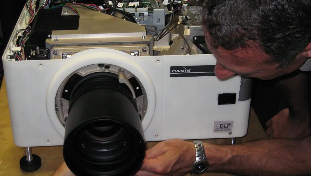 Engineer inspecting a white 3D-printed Christie projector prototype housing with lens