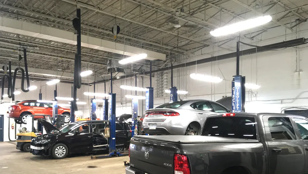 Vehicle repair shop lit by J2 Lights LED low-bay fixtures over the lifts