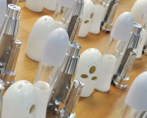 Rows of white and chrome handheld device prototypes lined up on a table
