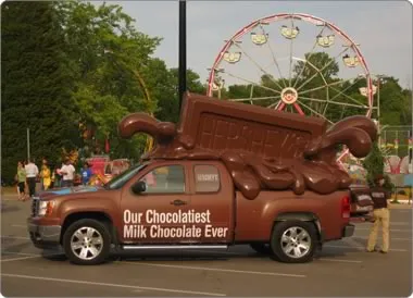 Hershey’s pickup truck wrapped in chocolate-brown graphics with a giant chocolate bar on top at a fairground
