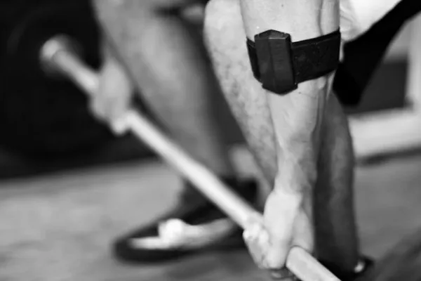 Push strength tracker strapped below a lifter knee during a barbell lift, in black and white