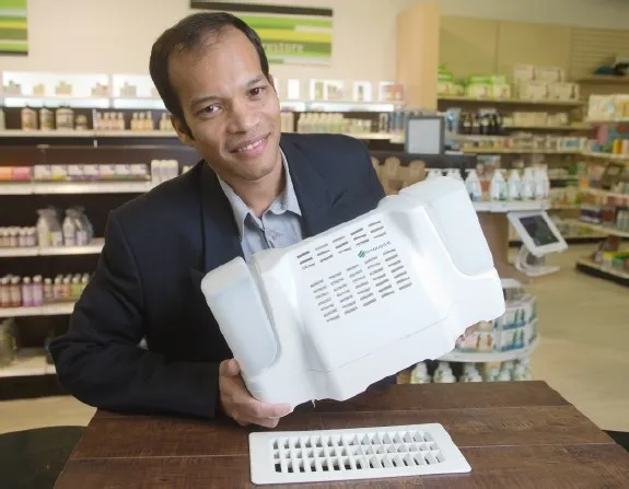 Man holding a white Rumidifier humidifier unit beside a floor vent register in a store