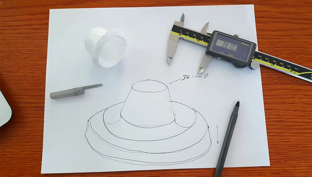 Pen sketch of a Keurig filter stand next to a paper filter and digital calipers reading 38.1 mm