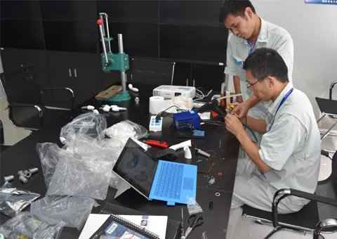 Two technicians assembling parts at a bench in a contract manufacturer’s lab