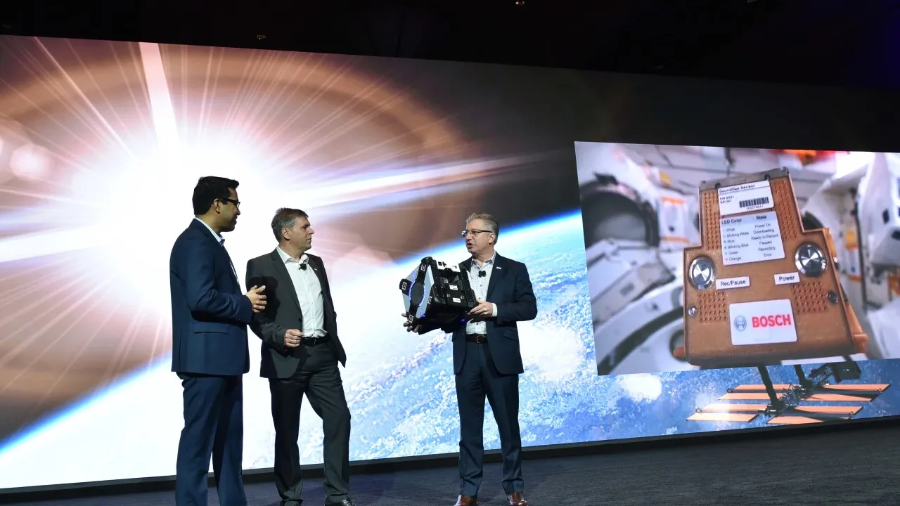 Three Bosch executives on the CES 2020 keynote stage holding a device beside a screen