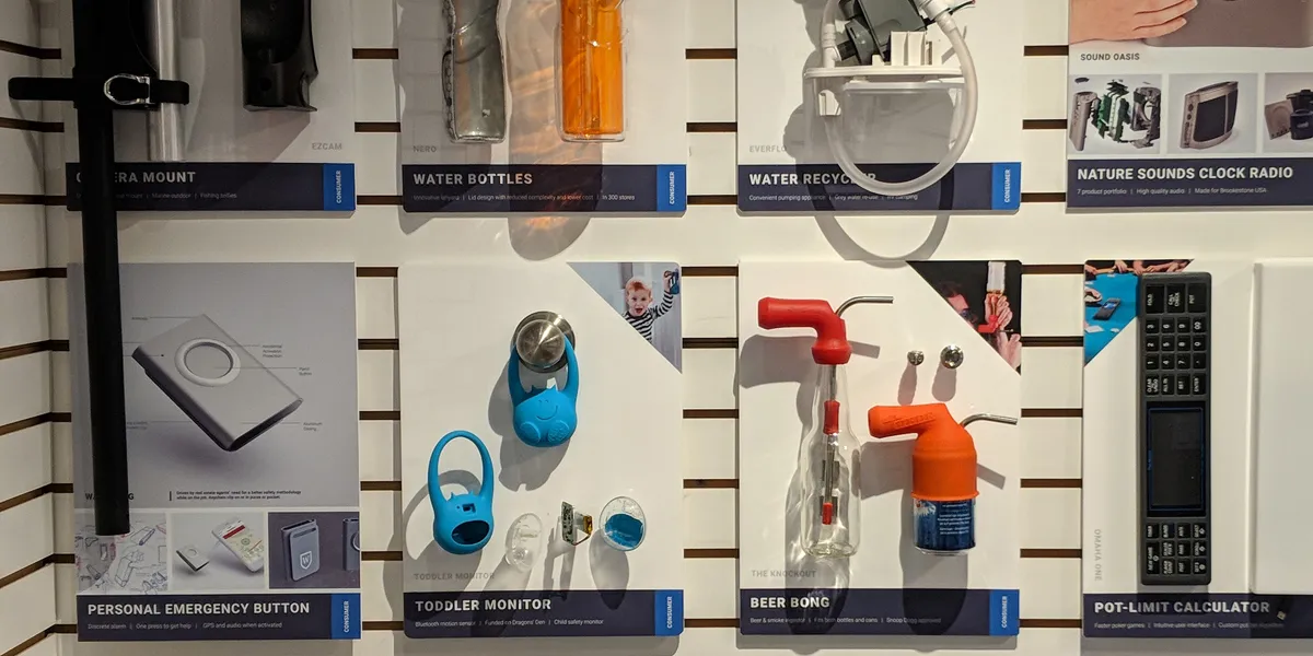 Boardroom display shelves with 3D product samples such as a toddler monitor, water bottles and a beer bong