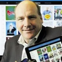 Grant Hall, CEO of Nuvyyo, holding a tablet showing a TV channel guide
