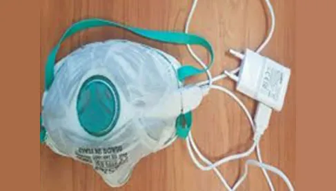 White respirator mask with a heated carbon-fibre layer plugged into a USB charger
