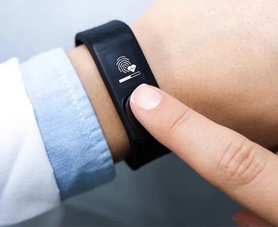 Finger pressing the sensor on a black Nymi band showing a fingerprint and heartbeat icon