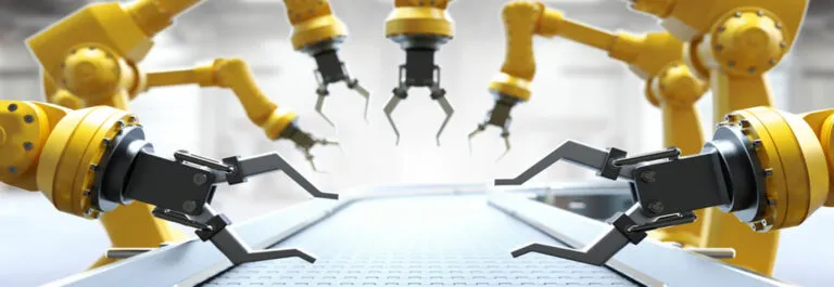 Yellow industrial robot arms with grippers positioned over an empty conveyor belt