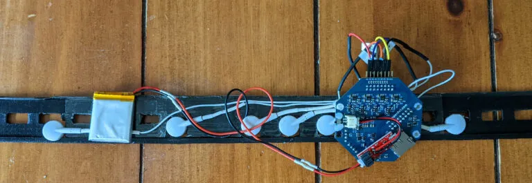 Prototype sensor headband with electrodes, battery and circuit board laid on a wooden floor
