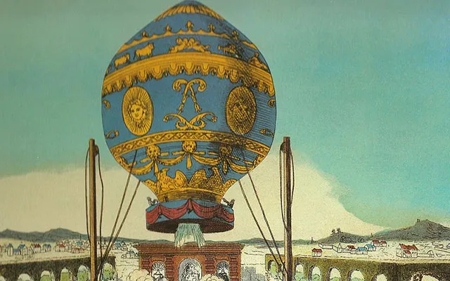 Vintage coloured print of an ornate blue and gold paper hot air balloon rising over a town
