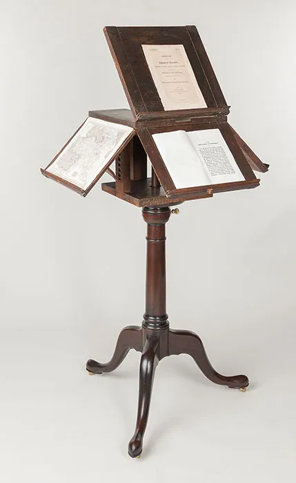 Antique wooden rotating reading desk on a tripod stand holding several open books