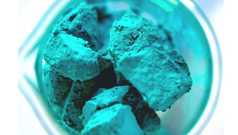 Chunks of Molecule turquoise desiccant nanomaterial in a glass beaker