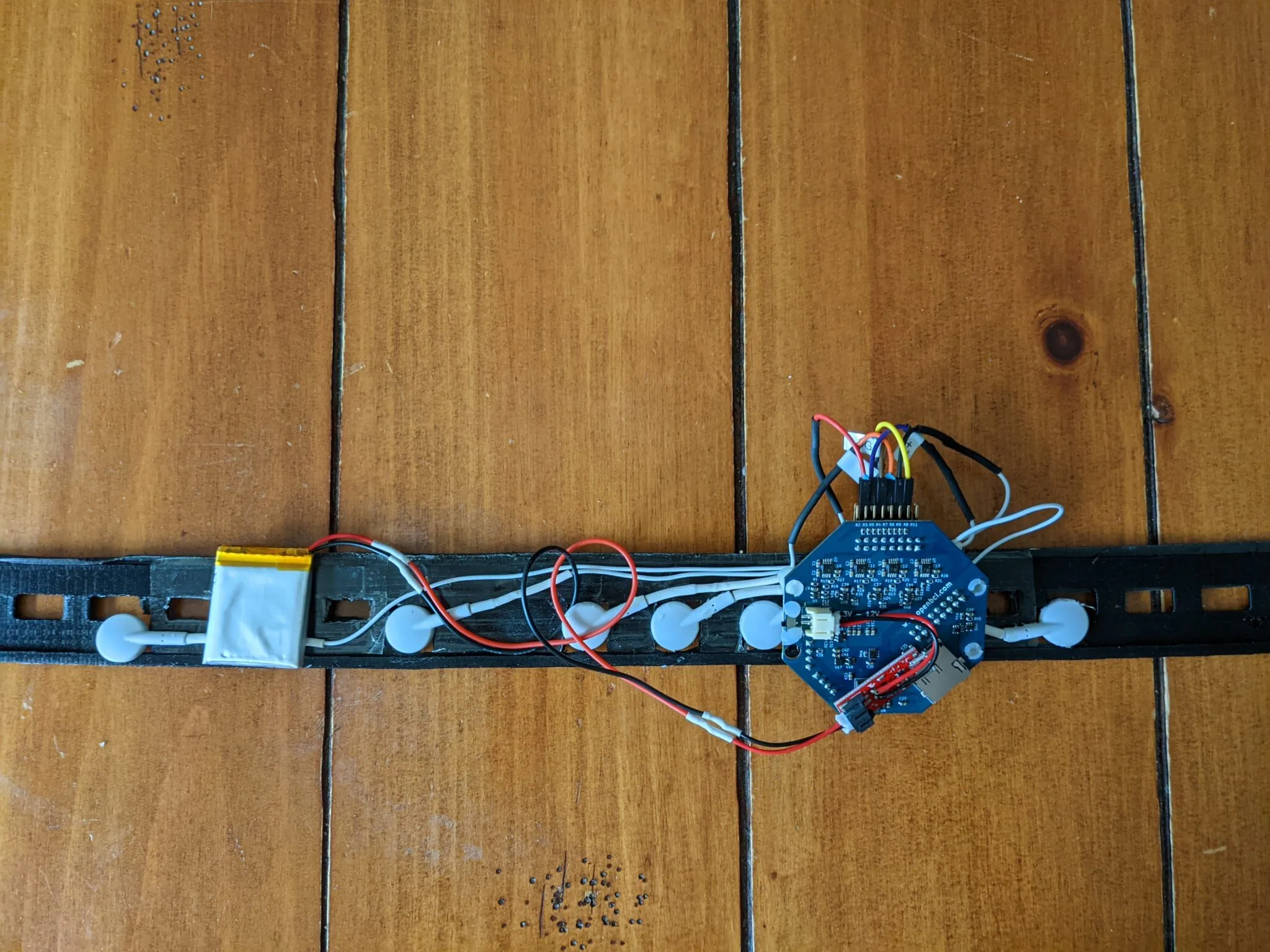 Neurovine bench model: circuit board, battery and electrode pads wired along a black strap
