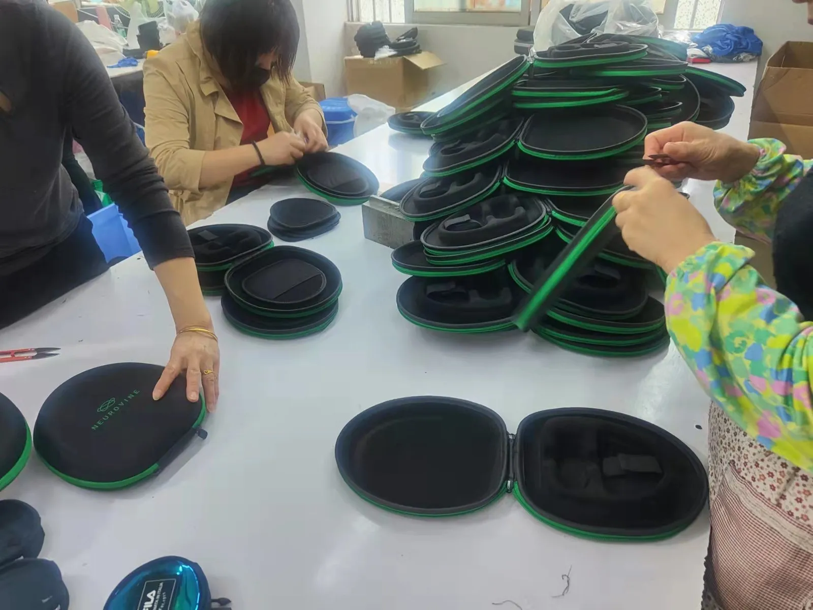 Factory workers assembling Neurovine zip cases on a production table