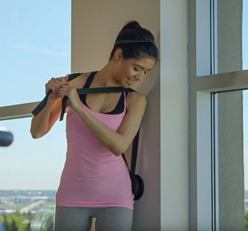 SoloRolo Context 3; woman using solorolo on her lower back against the wall in the gym